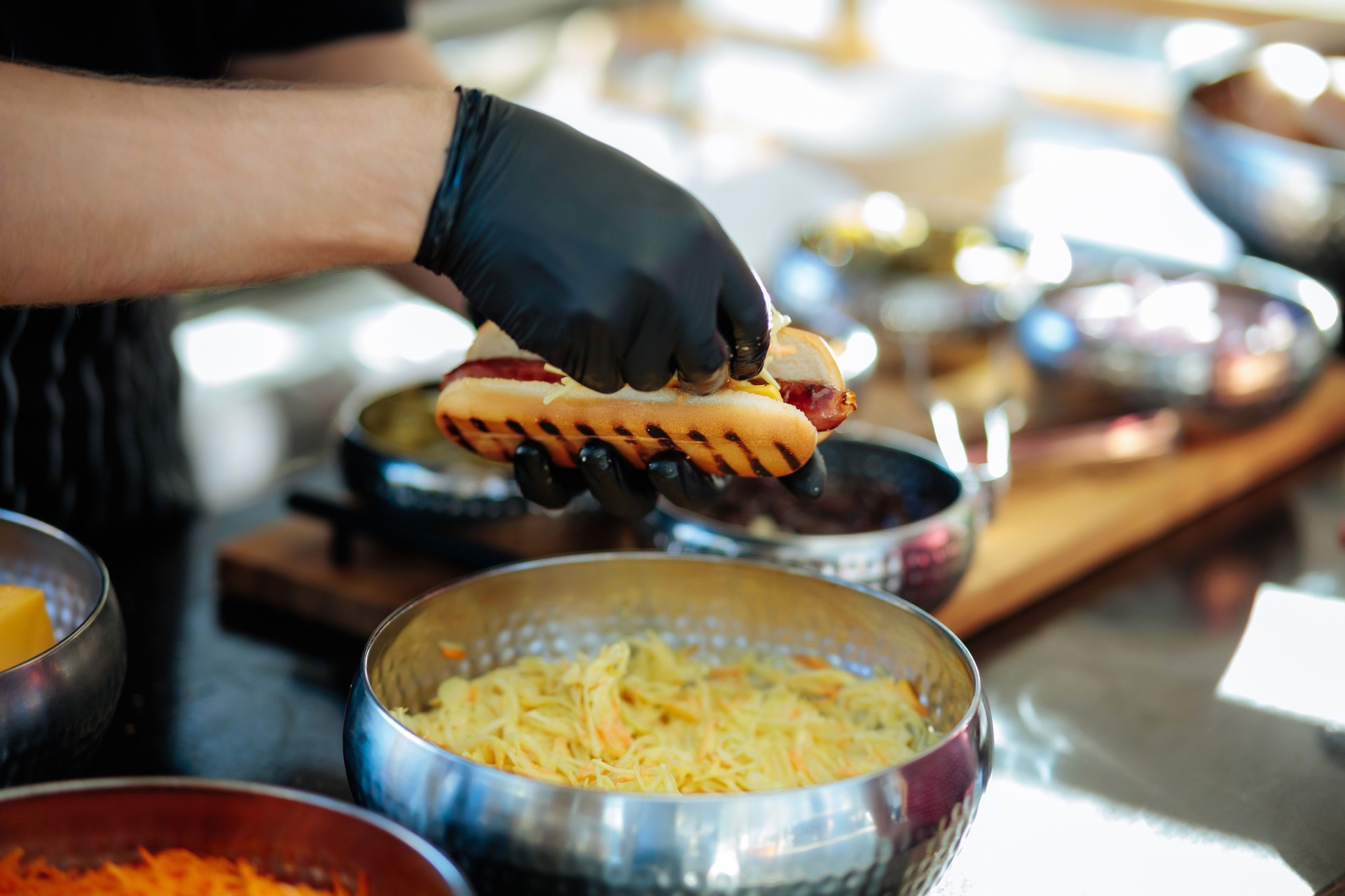 Preparing a gourmet hot dog with fresh toppings at a bustling food stand during
